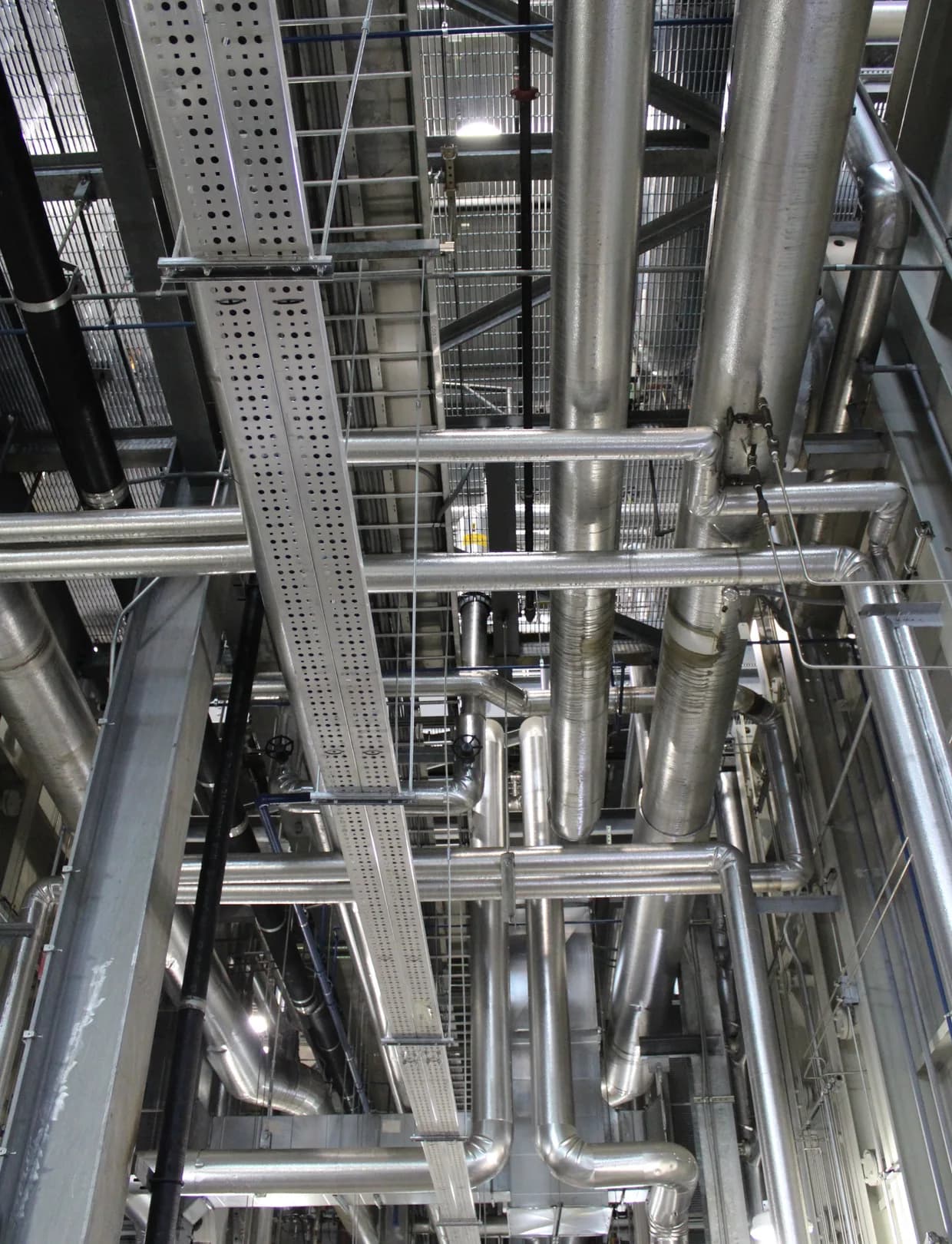 Verzweigte Rohrleitungen und Träger in einer Industrieanlage.
