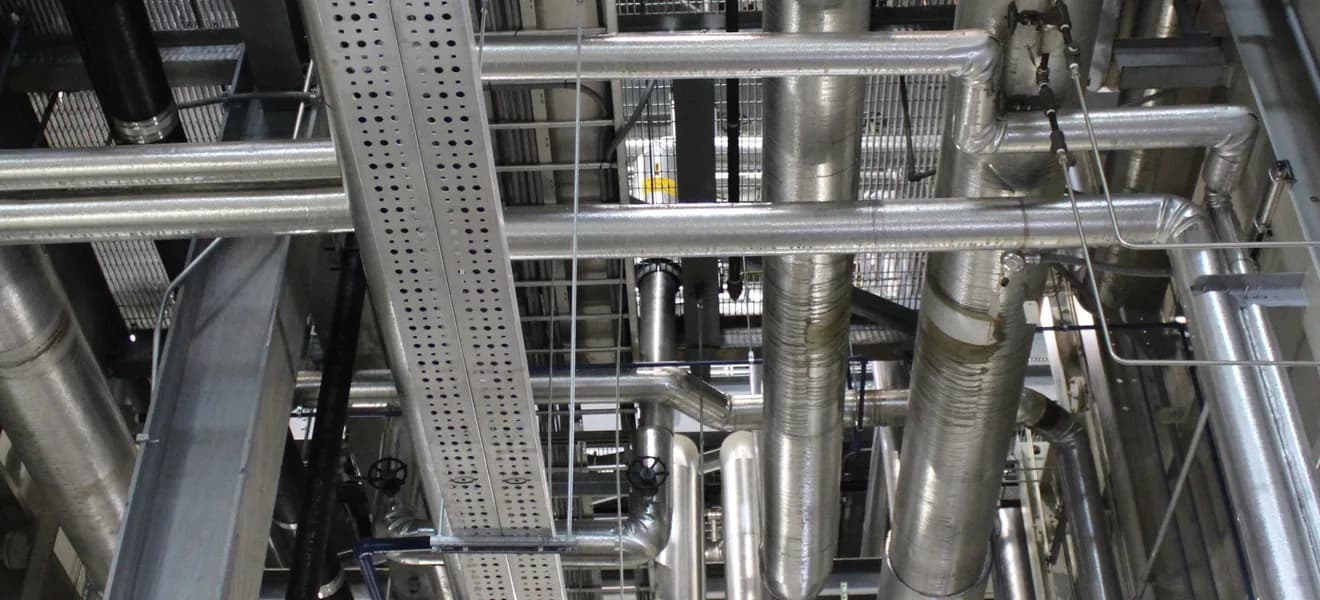 Verzweigte Rohrleitungen und Träger in einer Industrieanlage.