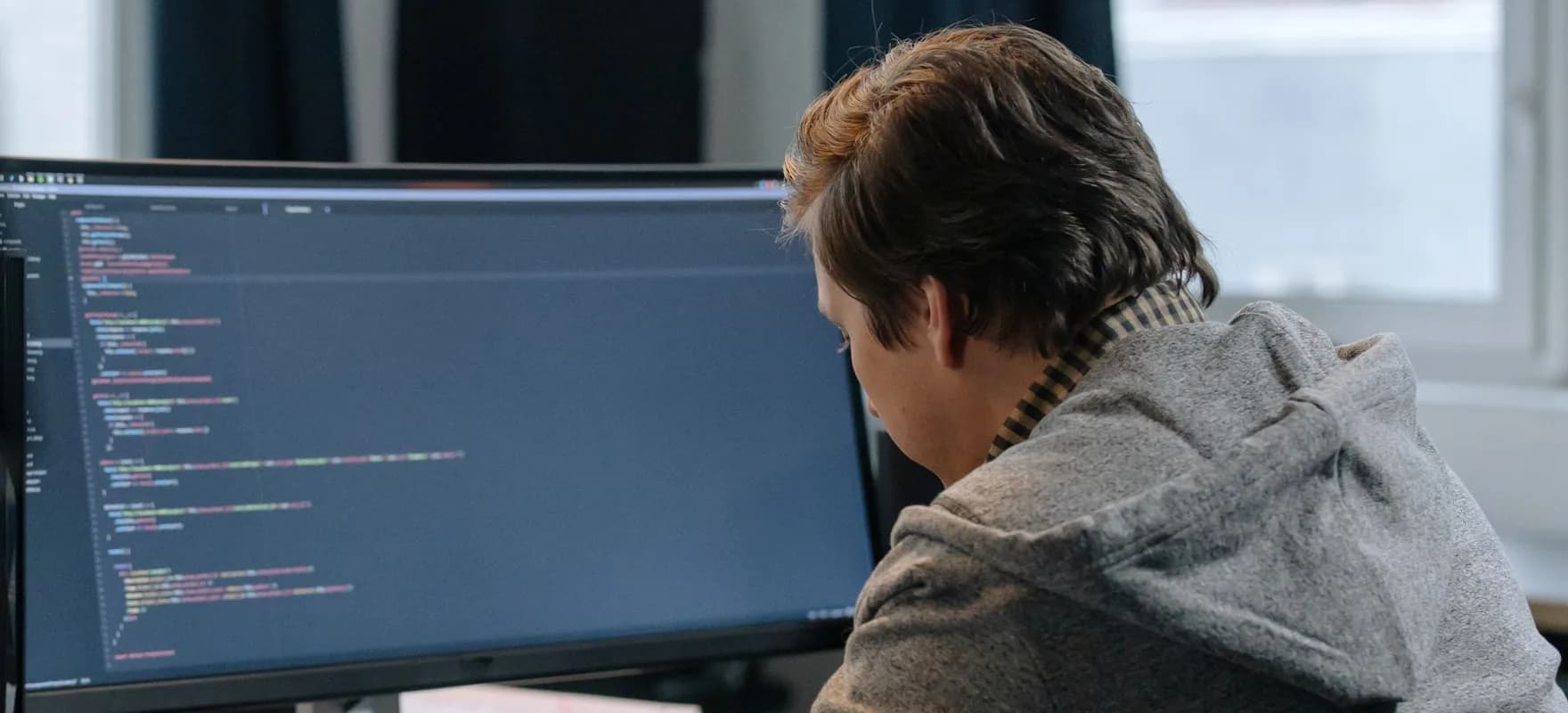 Eine Person tippt an einem Schreibtisch auf einer Computertastatur.