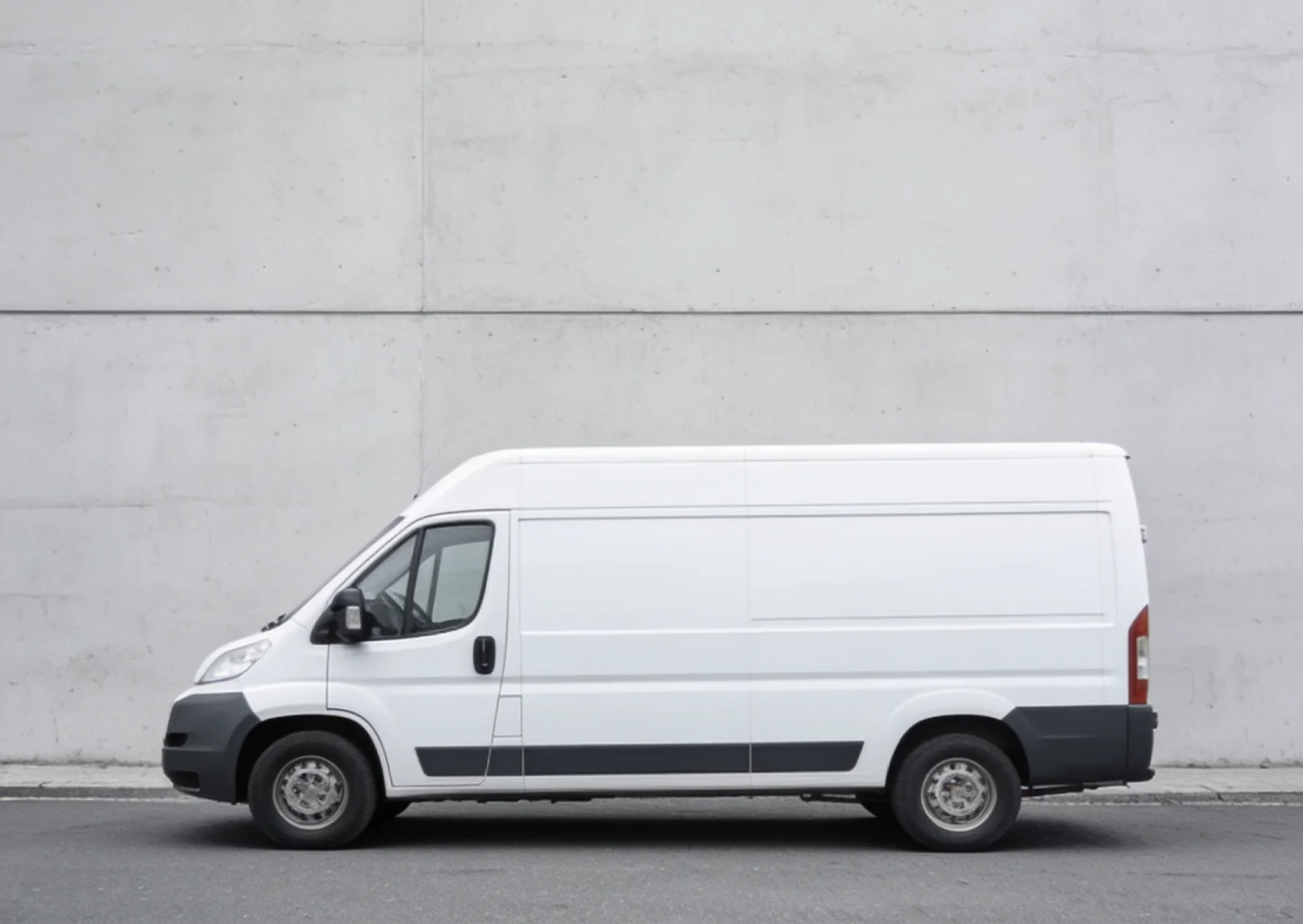 Ein weisser Transporter vor einer Betonwand.