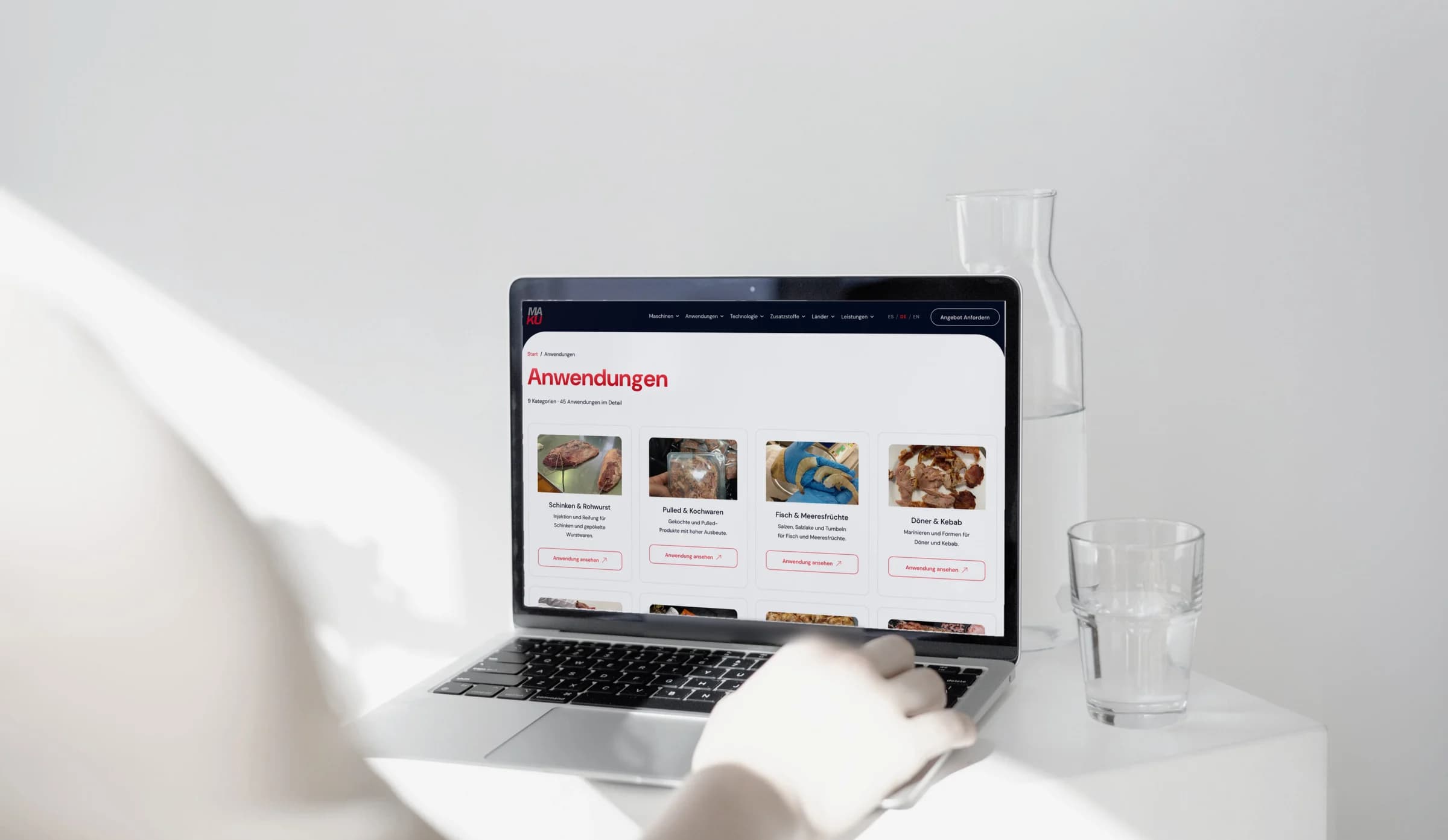 Eine Hand tippt auf einem MacBook, auf dem Bildschirm die Anwendungsseite von MAKU Meat Tec.